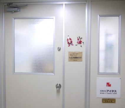 ▲アイタスオフィス入り口前。　ん？　サンタとトナカイの下、掲示板には……